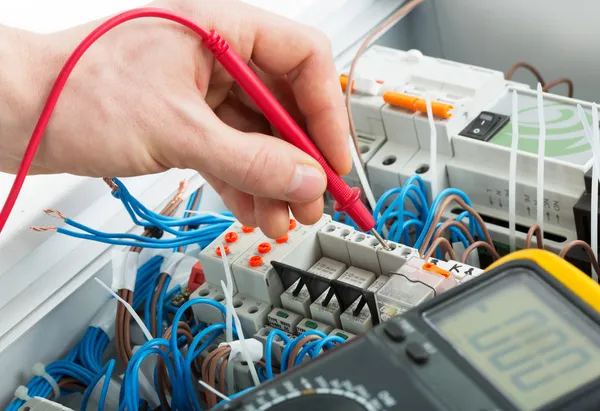 Electrician testing circuit breaker panel
